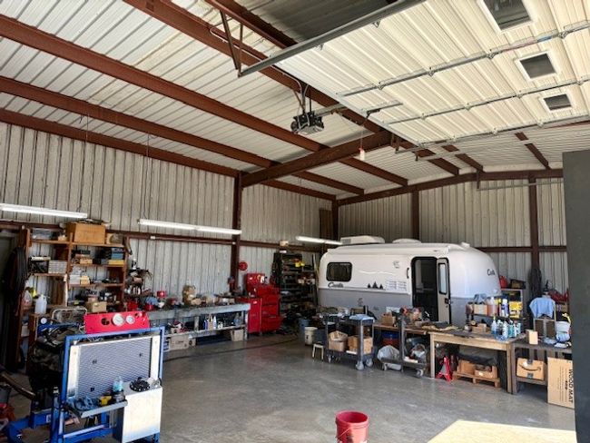 Garage with metal wall, a garage door opener, and a workshop area | Image 10