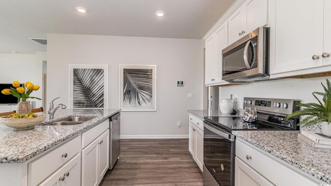 Kitchen with appliances with stainless steel finishes, a sink, dark wood-type flooring, white cabinetry, and recessed lighting | Image 11