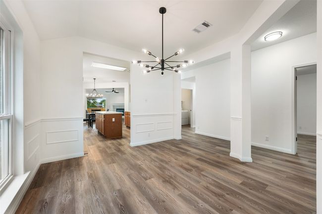Unfurnished living room featuring a chandelier, dark wood finished floors, and wainscoting | Image 8