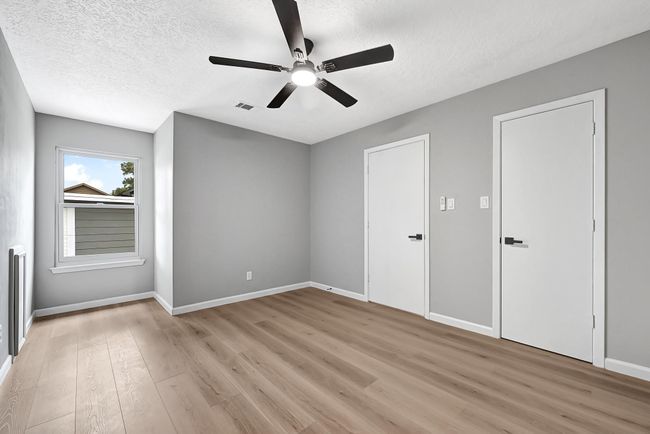 One of two upstairs bedrooms, this space features fresh neutral paint, sleek black hardware, and a modern ceiling fan. With luxury vinyl plank flooring and ample closet space, it’s a perfect setup for a guest room, home office, or kids’ room. | Image 36