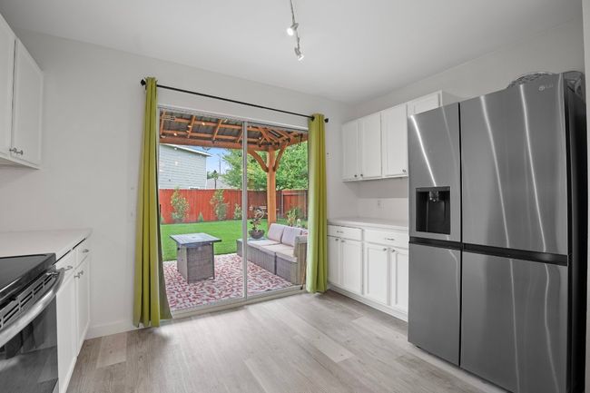 Kitchen with stainless steel appliances, light wood-style flooring, light countertops, and white cabinets | Image 9