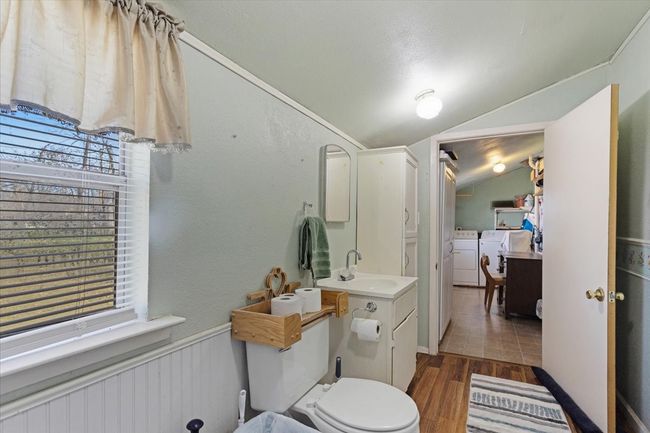 Bathroom with separate washer and dryer, lofted ceiling, hardwood / wood-style flooring, vanity, and toilet | Image 22