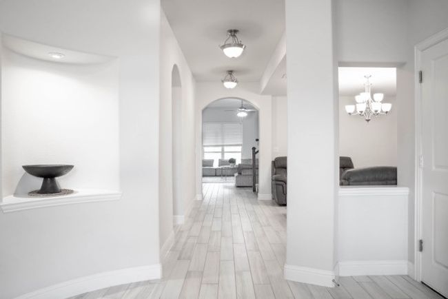 Corridor with an inviting chandelier, wood finished floors, baseboards, and arched walkways | Image 22