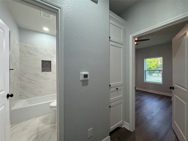 Full bath with a textured wall, bathing tub / shower combination, and wood finished floors | Image 21