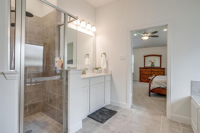 Bathroom with a ceiling fan, a shower stall, tile patterned flooring, and vanity | Image 25