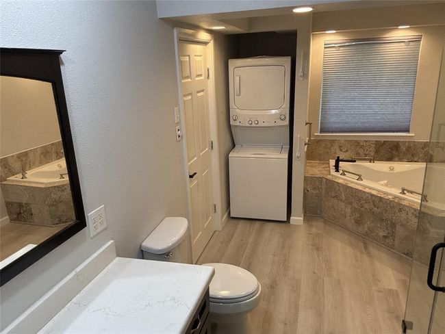 Explore the sleek, updated primary bath featuring a luxurious tub and convenient in-unit washer and dryer, included with the property. | Image 10