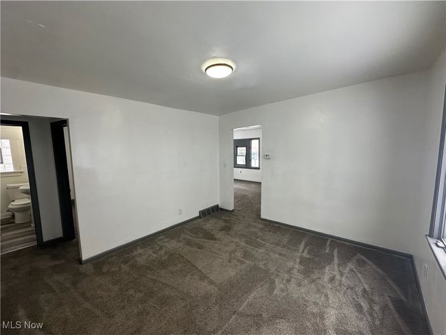 Empty room with visible vents, baseboards, and dark carpet | Image 24