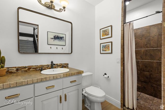 Full bath featuring vanity, toilet, a tile shower, and wood finished floors | Image 71