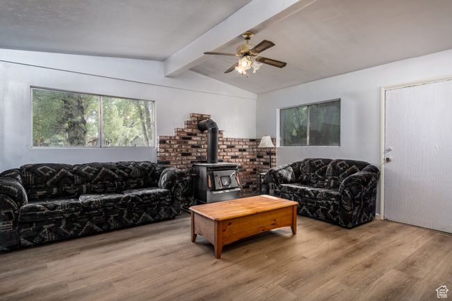 Living area featuring a wood stove, wood finished floors, and a ceiling fan | Image 15