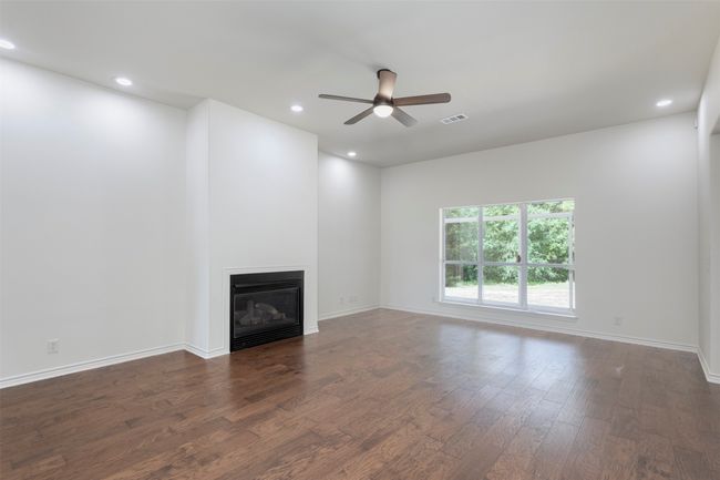 Unfurnished living room with ceiling fan, wood finished floors, a glass covered fireplace, recessed lighting, and baseboards | Image 6