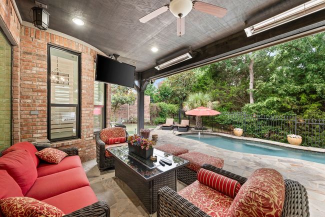 Covered stone paved patio with infrared heaters and ceiling fan enjoys a private park like view. | Image 30