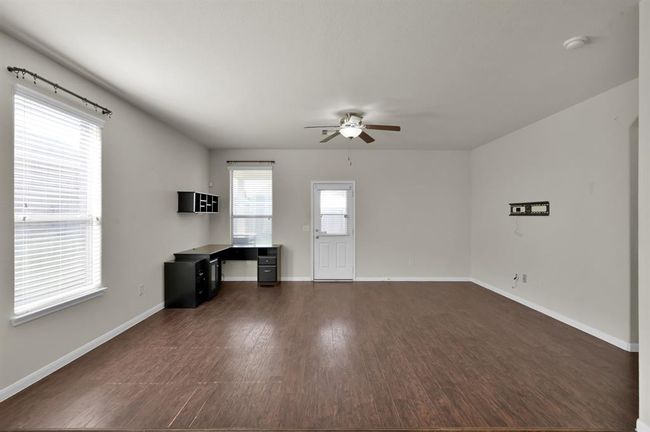 This open-concept living area features a blend of wood and tile flooring, ceiling fans, and a spacious kitchen with ample cabinetry and modern appliances, ideal for entertaining and family gatherings. | Image 14