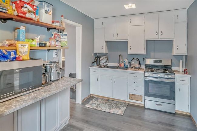 Kitchen with open shelves, wood finished floors, a sink, light countertops, and appliances with stainless steel finishes | Image 7