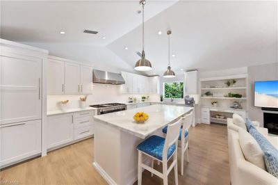 Kitchen with range, white cabinetry, light hardwood / wood-style flooring, and wall chimney exhaust hood | Image 3