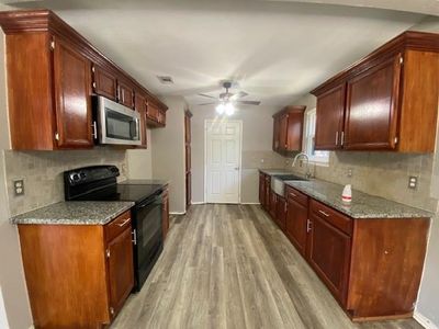 Kitchen with ceiling fan, light hardwood / wood-style flooring, black range with electric cooktop, and decorative backsplash | Image 2