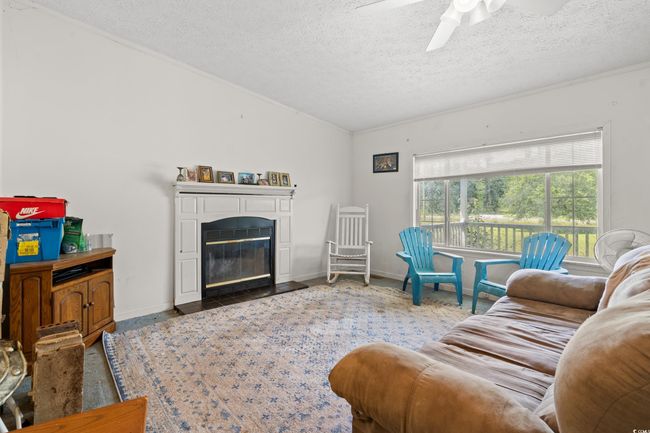Living room featuring a textured ceiling, lofted ceiling, ceiling fan, and a fireplace with flush hearth | Image 17