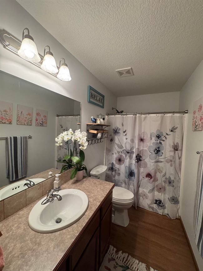 Full bath with wood finished floors, a textured ceiling, toilet, vanity, and a shower with curtain | Image 19
