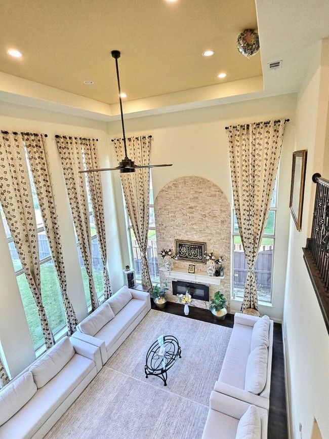 Living room featuring a tray ceiling, a glass covered fireplace, recessed lighting, and a high ceiling | Image 7