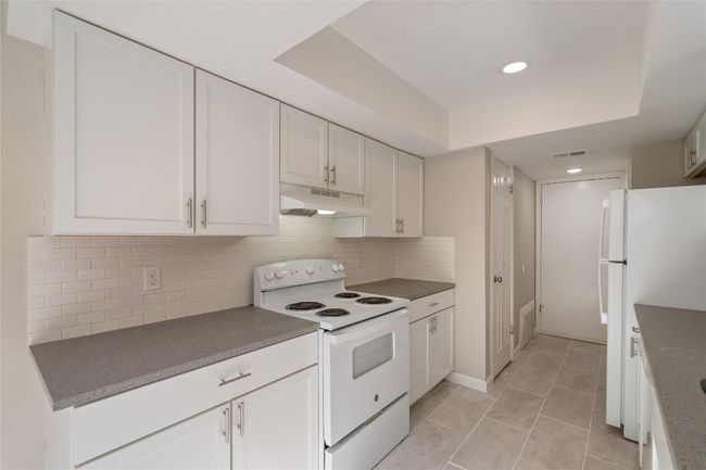 Updated galley kitchen with sleek quartz countertops, white shaker cabinets, subway tile backsplash, and all-white appliances — stylish and functional! | Image 5