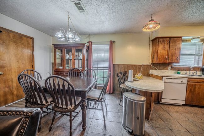 Dining room with a textured ceiling, a chandelier, wainscoting, and wooden walls | Image 14
