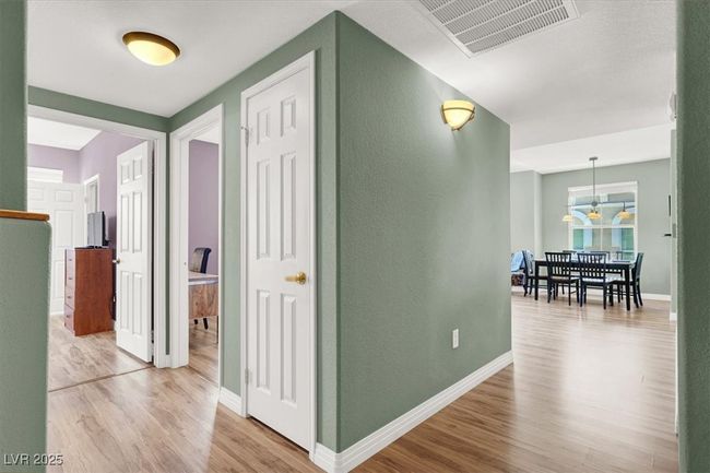 Corridor with wood like finished floors, visible vents, a textured wall, and baseboards | Image 6