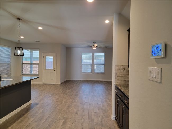 Kitchen featuring stone counters, light wood-style flooring, pendant lighting, baseboards, and a ceiling fan | Image 7