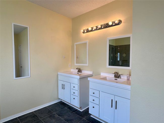 Bathroom with two vanities, tile patterned flooring, and a shower with shower door | Image 12