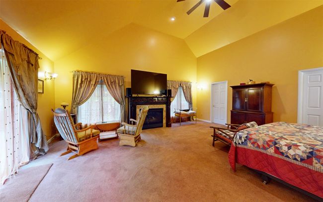 Bedroom featuring high vaulted ceiling, carpet floors, a glass covered fireplace, baseboards, and a ceiling fan | Image 39