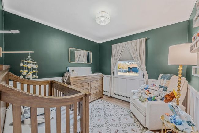 Bedroom featuring a nursery area, a baseboard heating unit, and light hardwood / wood-style flooring | Image 15