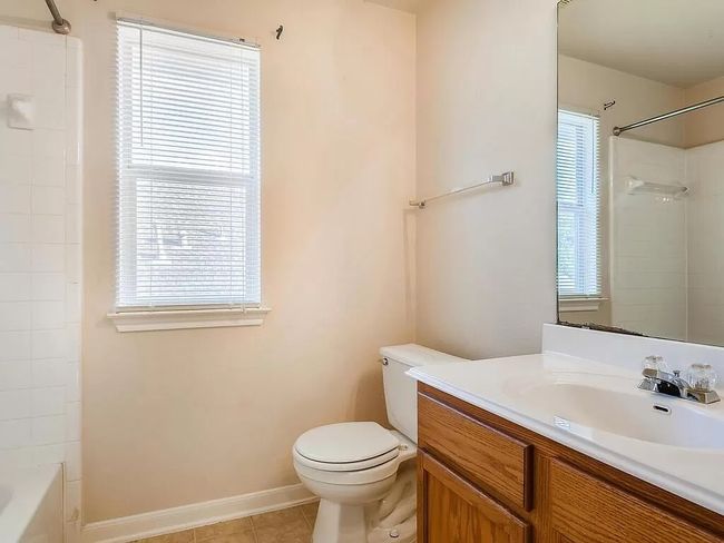 Bathroom with vanity, toilet, baseboards, tile patterned flooring, and washtub / shower combination | Image 22