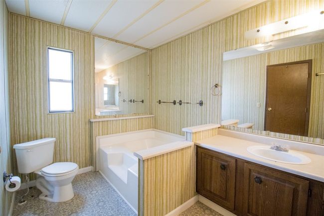 Full bathroom featuring a garden tub, vanity, and wallpapered walls | Image 9