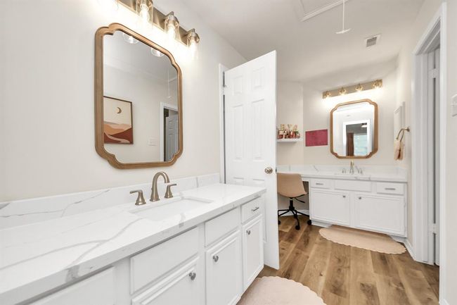 This well-designed bathroom connects directly to one bedroom and also has a separate door for easy access from the other secondary bedrooms. With two sinks, plenty of counter space, crisp white cabinetry, and a private walk-in shower, it offers both convenience and functionality—perfect for a growing family. | Image 37