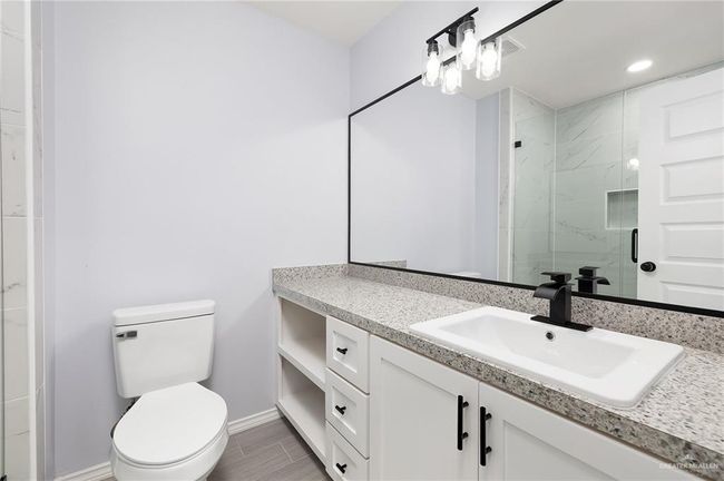Bathroom featuring vanity, a marble finish shower, toilet, baseboards, and recessed lighting | Image 10