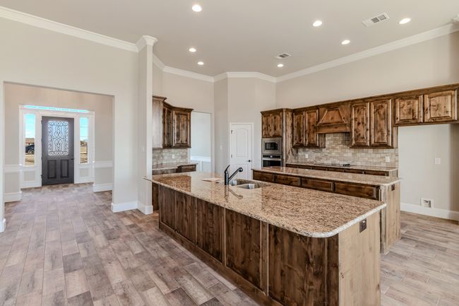 Kitchen featuring a large island, stainless steel appliances, decorative backsplash, light wood-style flooring, and ornamental molding | Image 6