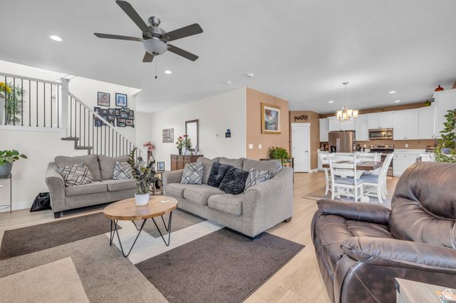 Living area featuring ceiling fan with notable chandelier, recessed lighting, light wood-type flooring, and stairway | Image 5