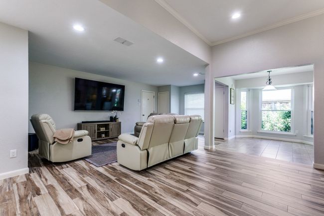 Living room with wood finished floors, crown molding, and recessed lighting | Image 5
