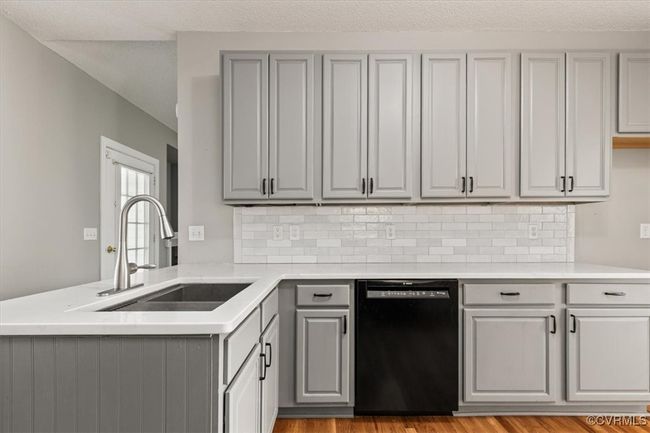 Kitchen featuring gray cabinets, black dishwasher, a sink, a peninsula, and light countertops | Image 15