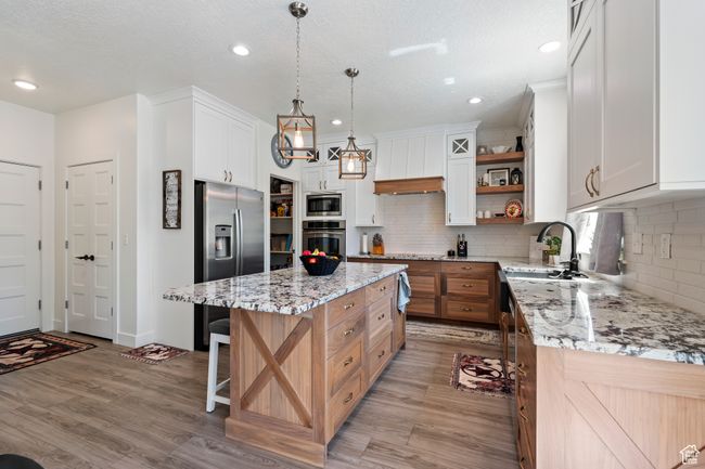 Kitchen with open shelves, a sink, light wood-style floors, appliances with stainless steel finishes, and a kitchen island | Image 17
