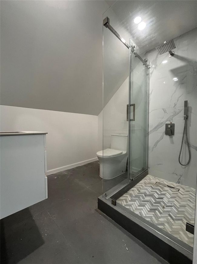 Bathroom with baseboards, vaulted ceiling, a marble finish shower, and toilet | Image 7