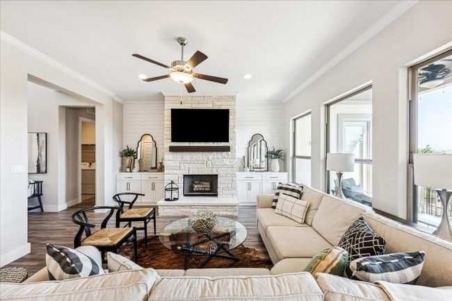 The main focal point of the room is the floor-to-ceiling stone fireplace with a raised hearth and cedar mantle, while custom cabinets with shiplap wall panels on both sides add warmth and charm. | Image 8