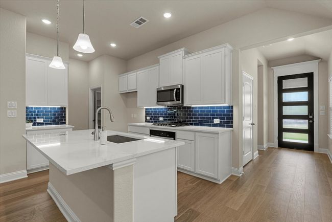Kitchen with a sink, stainless steel microwave, light wood-style floors, and backsplash. | Image 5
