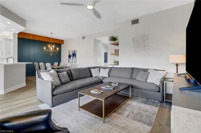 Living room featuring ceiling fan with notable chandelier and light hardwood / wood-style flooring | Image 2