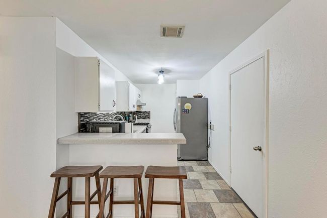 Kitchen with decorative backsplash, visible vents, light countertops, and freestanding refrigerator | Image 13