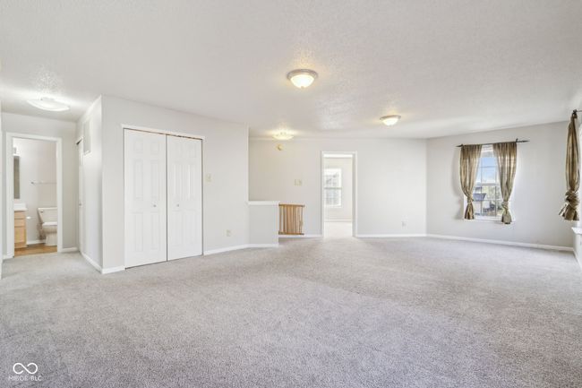 unfurnished living room with a textured ceiling, healthy amount of natural light, carpet floors, and baseboards | Image 52