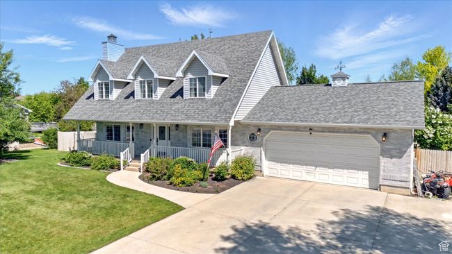 Cape cod home with concrete driveway, a shingled roof, an attached garage, and covered porch | Image 35