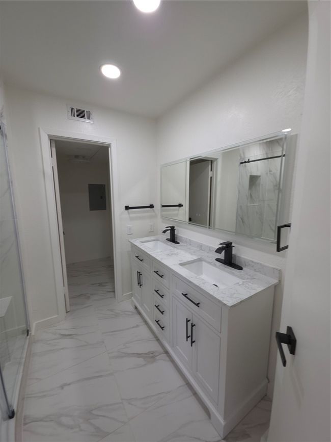 Full bath featuring marble look tile flooring, double vanity, recessed lighting, a marble finish shower, and electric panel | Image 14
