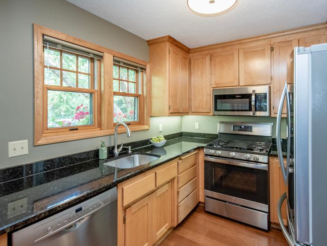 The updated kitchen boasts granite countertops, newer cabinetry, and sleek stainless steel appliances. | Image 13