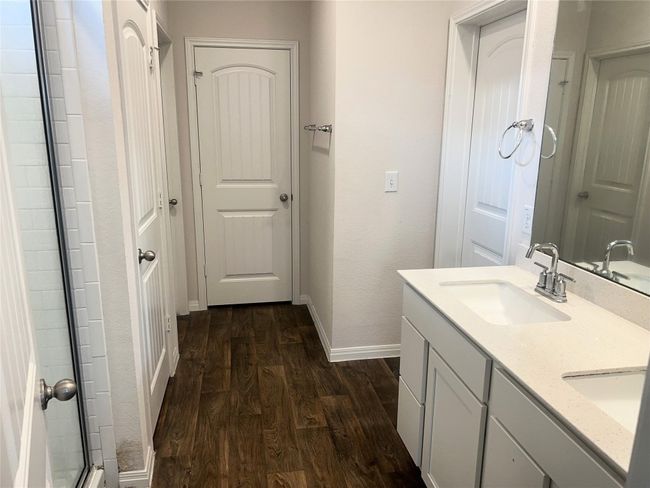 Full bathroom featuring wood finished floors, baseboards, double vanity, and an enclosed shower | Image 12