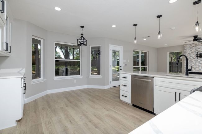 Kitchen with dishwasher, white cabinets, light wood finished floors, hanging light fixtures, and recessed lighting | Image 21