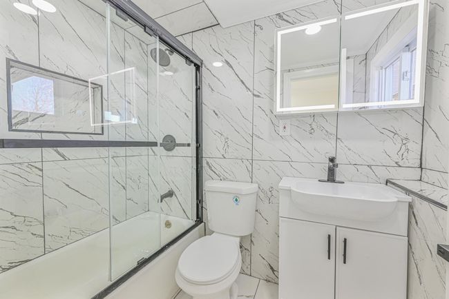 Full bathroom with vanity, bath / shower combo with glass door, toilet, and plenty of natural light | Image 36